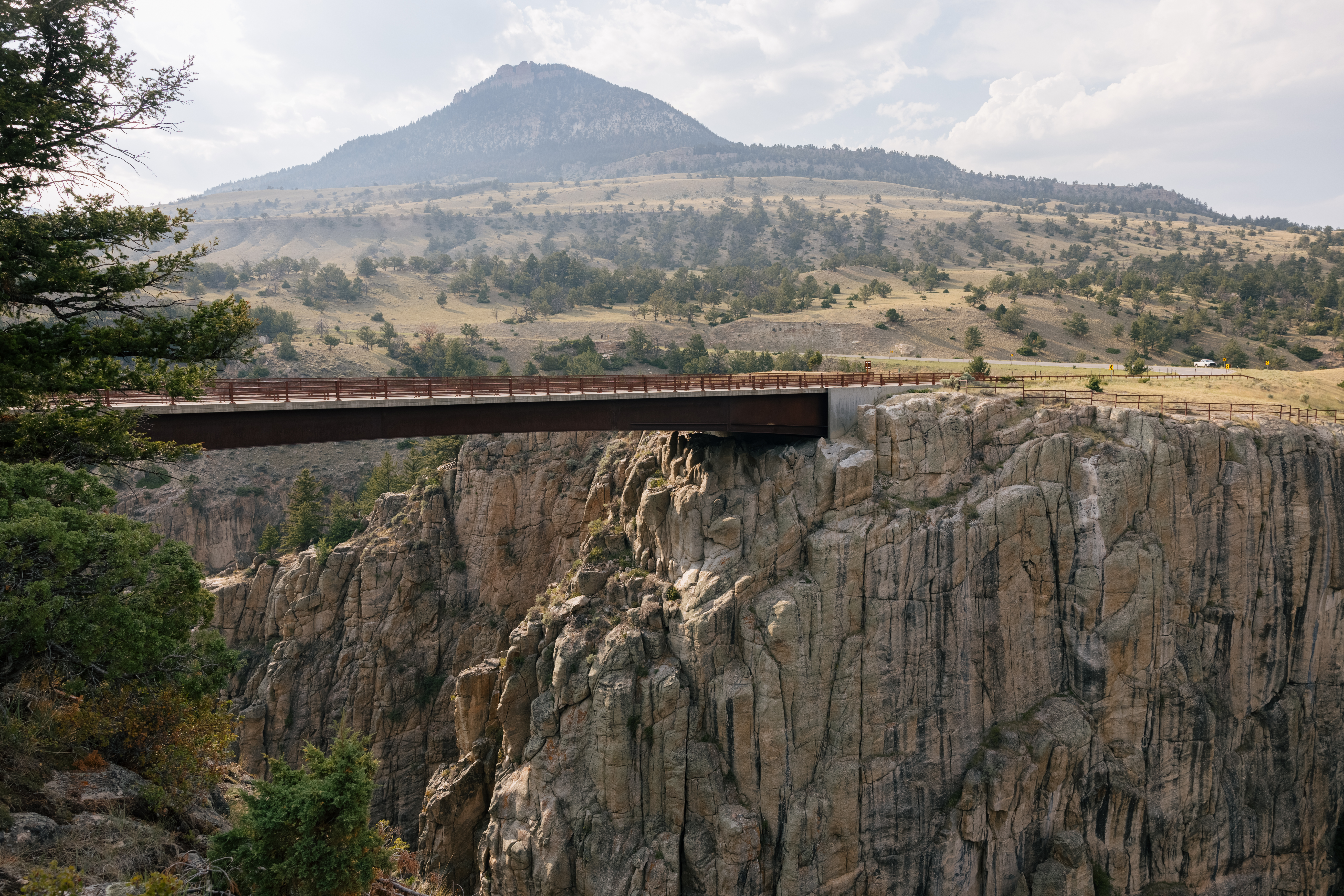 Modern bridge spanning rocky canyon with mountains